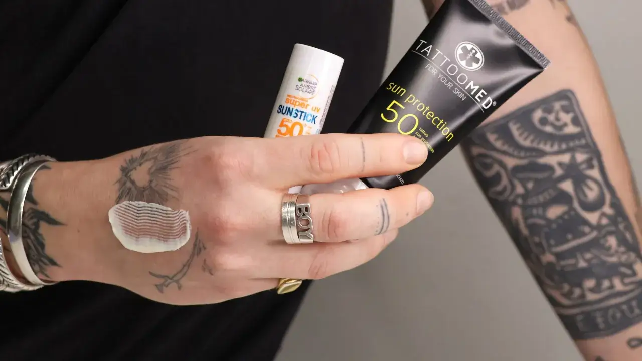H&auml;nde mit Tattoos halten Sonnencreme. Die Frage 