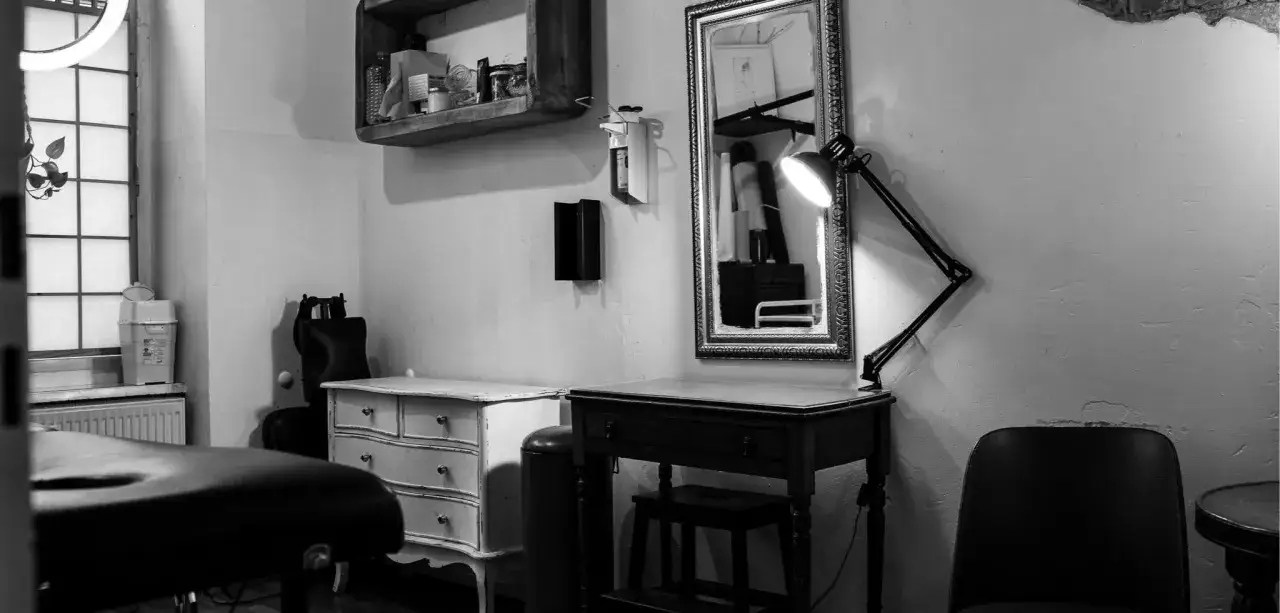 Ein Tattoo-Studio mit Liege, Spiegel und Lampe. Hier wird die Frage beantwortet: wie lange dauert ein kleines Tattoo?