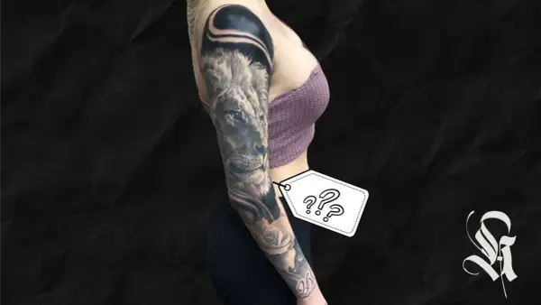 Ein beeindruckendes, all black tattoo ziert den Arm einer Frau. Ein Löwe blickt majestätisch, umgeben von Rosen und abstrakten Formen.