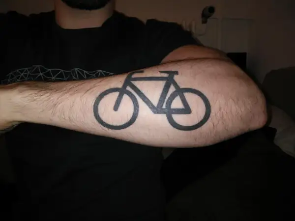 Schwarzes Fahrrad-Tattoo auf einem behaarten Arm. Ein Symbol für die Liebe zum Radfahren nach dem Tattoo.