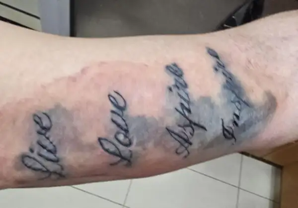 Tattoo mit den Worten "Live", "Love", "Aspire", "Inspire". Die Linien sind etwas unscharf, was auf einen Tattoo Blowout oder eine normale Heilung hindeuten könnte.