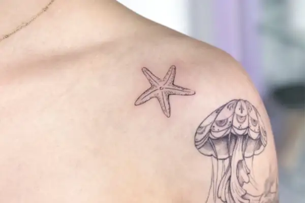 Kleines Seestern-Tattoo auf der Brust, neben einer Qualle.