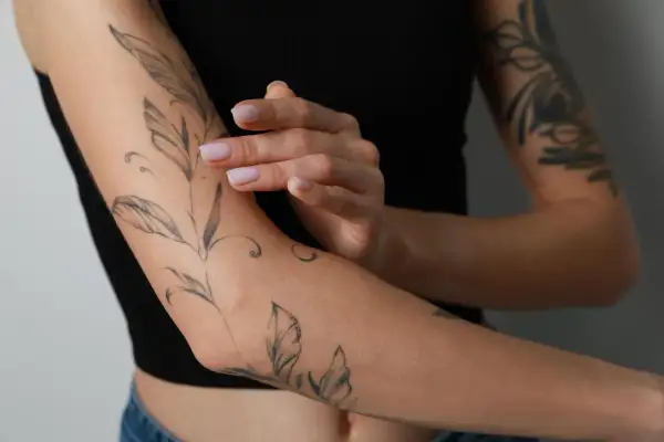 Frauenarm mit Blatt-Tattoo. Das Tattoo schmerzt nach 4 Tagen, die Haut ist leicht gerötet.