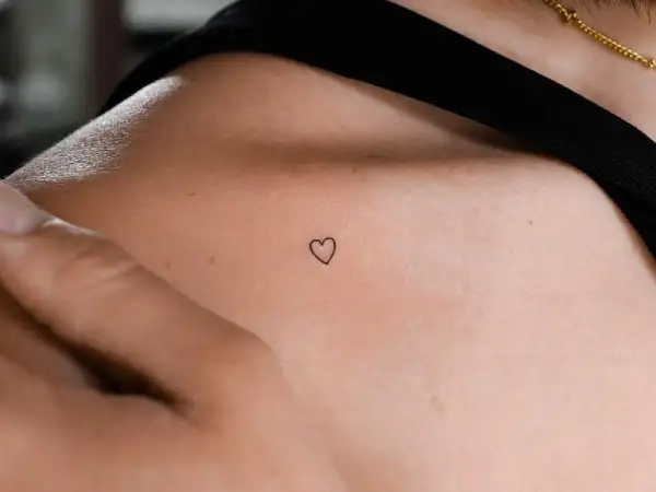 Kleines Herz-Freundschaftstattoo auf der Schulter einer Frau, ein zartes Symbol ewiger Verbundenheit.