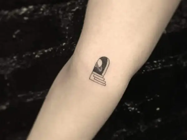 Ein kleines Tattoo auf dem Arm eines Mannes zeigt eine Tür mit Stufen, die zu einem Planeten führt.