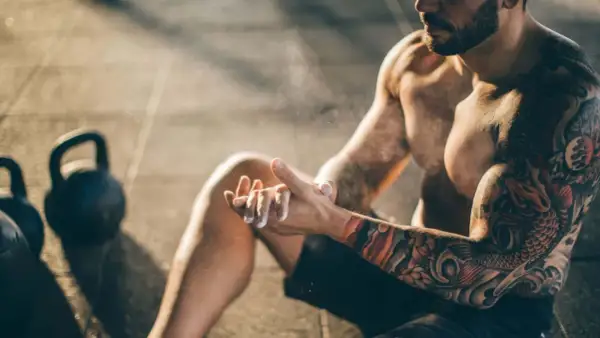 Mann mit beeindruckendem Tattoo auf Brust und Arm, der sich für das Training vorbereitet.