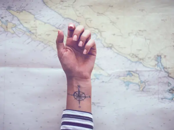 Ein feminines Kompass-Tattoo auf dem Handgelenk, bereit für das nächste Abenteuer auf der Seekarte.